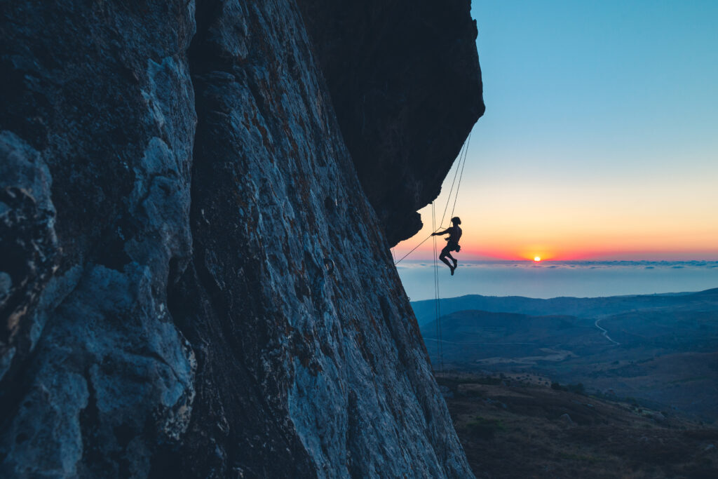 Climber on mountain, sun setting in the background